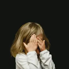 Dziecko zakrywa oczy dłońmi. Szukamy sposobów na rozładowanie emocji u dzieci, by mogły swobodnie wyrażać siebie.