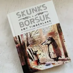 Skunks i Borsuk – idealne książki na dobranoc. Ilustracja przedstawia dwóch borsuków w płaszczach, jeden z walizką, gotowych na przygodę.