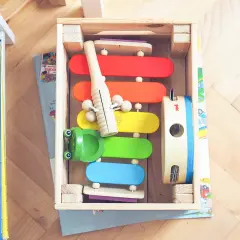 Kolorowy kącik matematyczny z cymbałkami, żabką i tamburynem w drewnianej skrzynce.