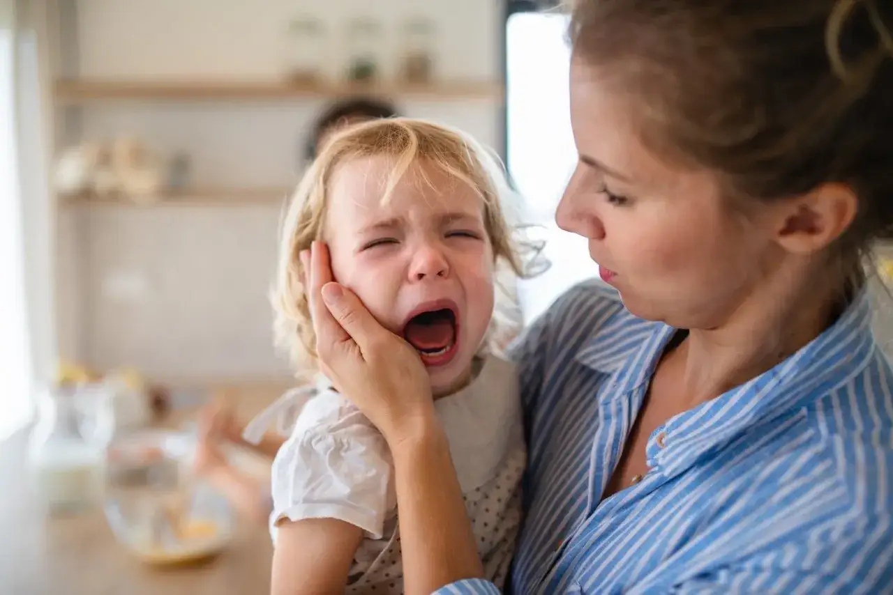 Mama pociesza płaczące dziecko, które przeżywa lęk separacyjny u 2-latka.